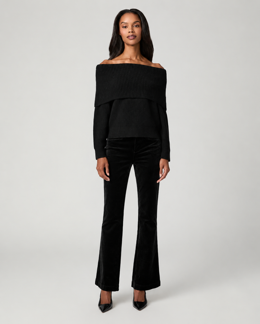 A model wearing a black off-the-shoulder long-sleeve top and matching black flared pants, standing against a light gray studio background.