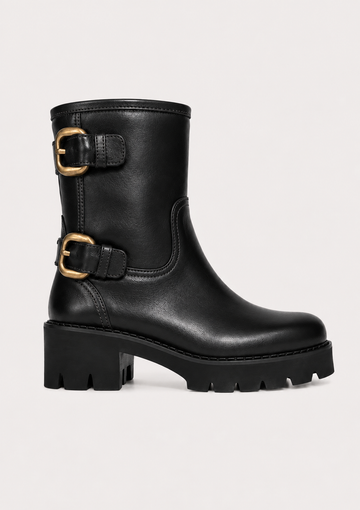 A black leather mid-calf boot with two gold-tone buckle straps and a chunky lug sole, shown against a plain light background.
