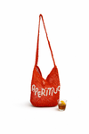 Red woven bag with 'Aperitivo' text next to a glass of juice on a white background