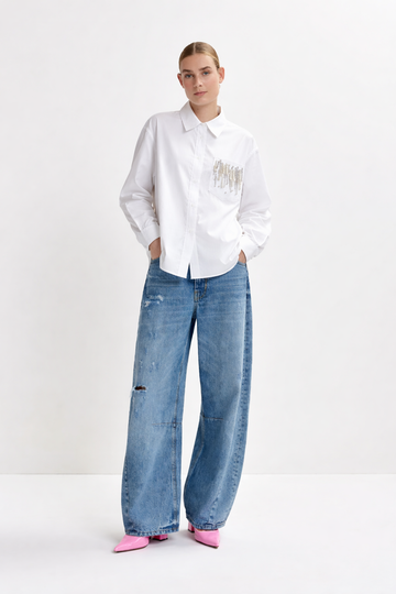 Person wearing a white shirt with text and blue jeans on a white background