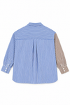 A long-sleeve button-up shirt shown from the back, featuring vertical blue and white stripes on the main body, a solid blue horizontal stripe across the upper back, and brown and white vertical stripes on the right sleeve.