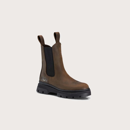 A single brown leather Chelsea-style boot with black elastic side panels and a chunky black sole, photographed on a plain light beige background.