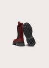 A pair of red suede Chelsea-style boots with black elastic side panels and black lug soles, shown from the back on a light gray background.