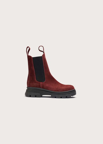 A single dark red suede Chelsea boot with a black elastic side panel and a chunky black lug sole, shown in profile against a light beige background.