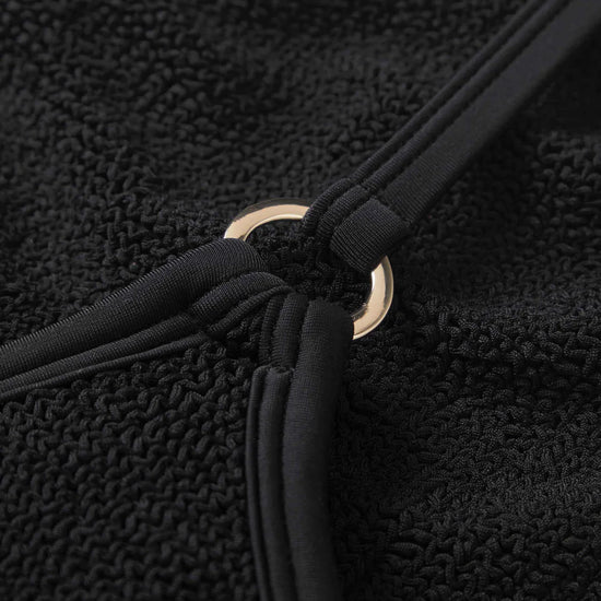 Close-up of a black textured fabric with a gold ring detail.