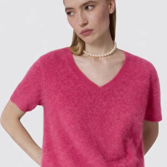 Woman wearing a pink sweater against a plain background