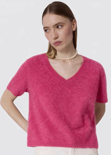 Woman wearing a pink sweater against a plain background