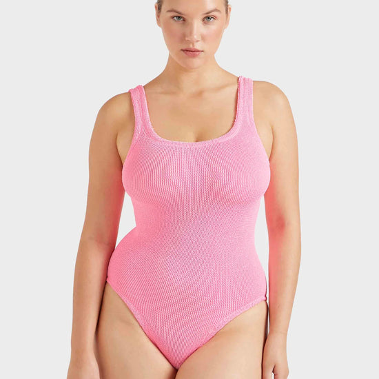 Woman wearing a pink ribbed swimsuit on a white background