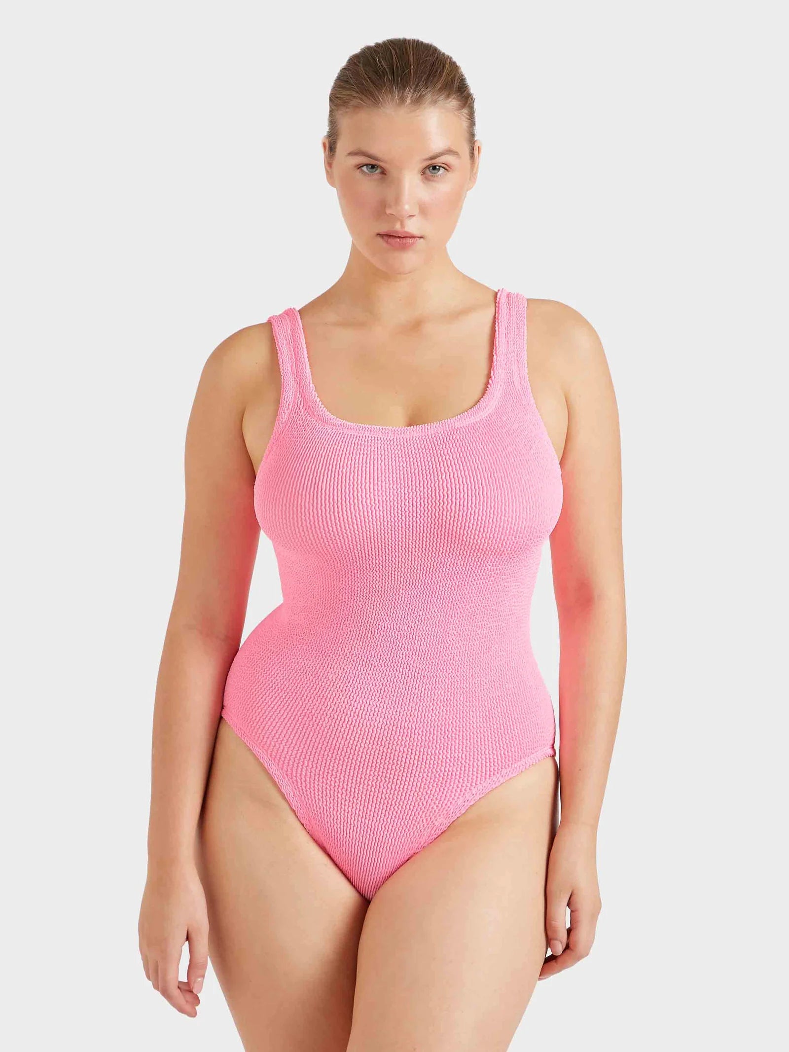 Woman wearing a pink ribbed swimsuit on a white background