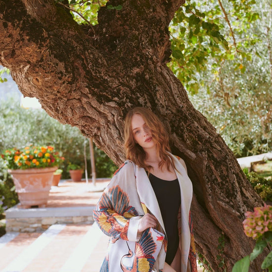 Woman leaning against a large tree in a garden setting wearing a 100 stars gown