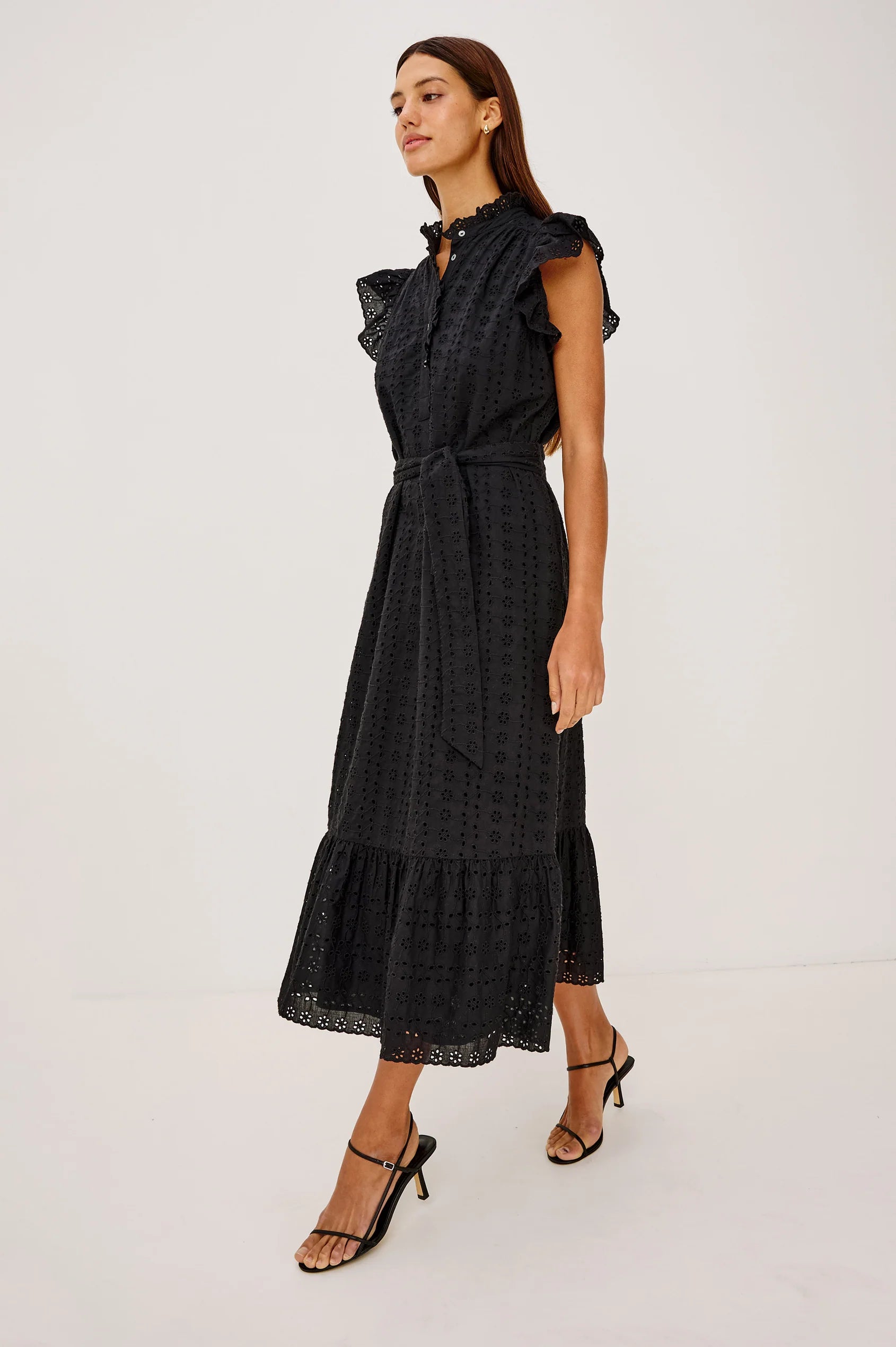 Woman wearing a black dress with ruffled details on a white background