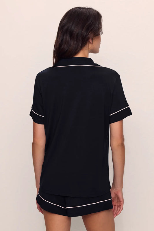 Person wearing a black pajama set with white piping from Eberjey