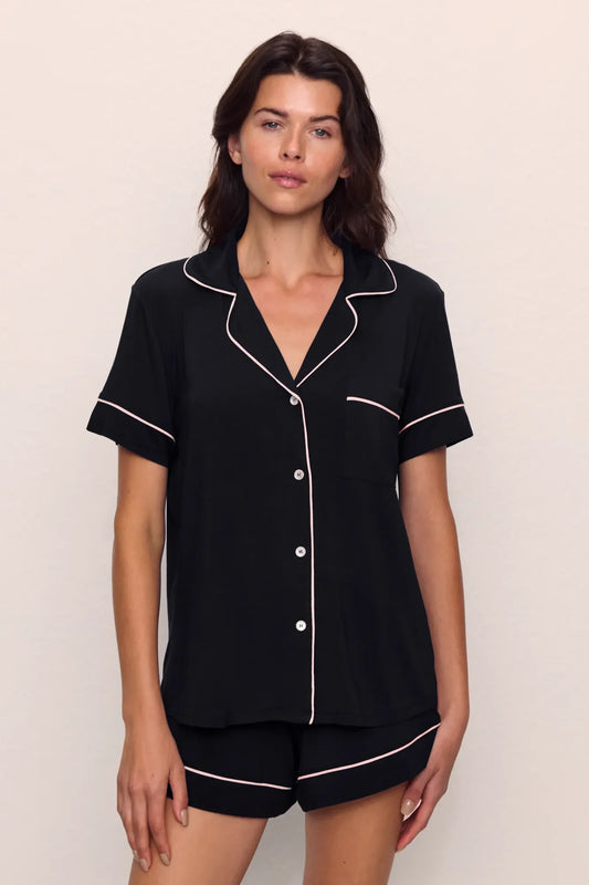 Woman wearing a black pajama set with white piping from Eberjey