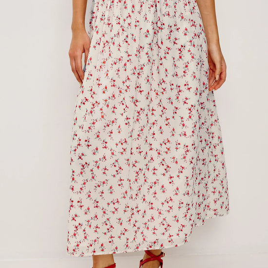 Person wearing a floral skirt with red flowers on a white background