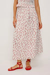 Person wearing a floral skirt with red flowers on a white background