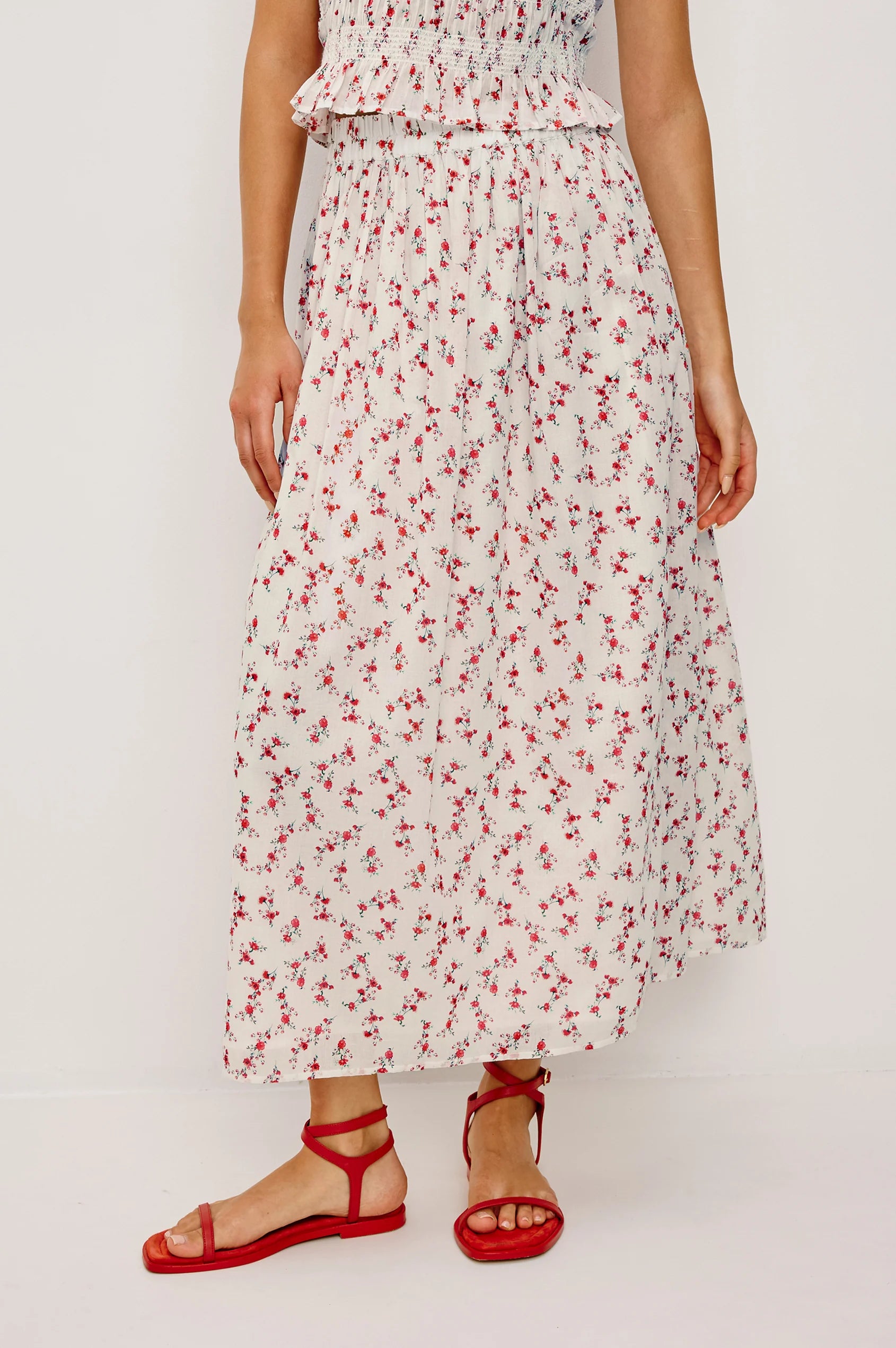 Person wearing a floral skirt with red flowers on a white background