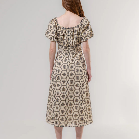 Woman wearing a patterned dress on a plain background
