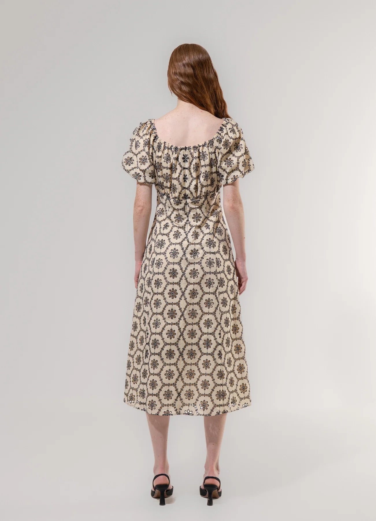 Woman wearing a patterned dress on a plain background
