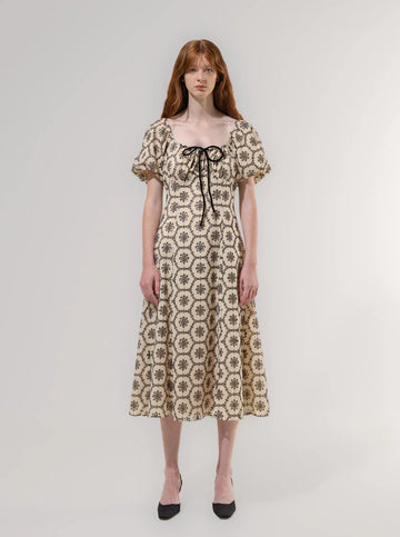 Woman wearing a floral patterned dress on a plain background