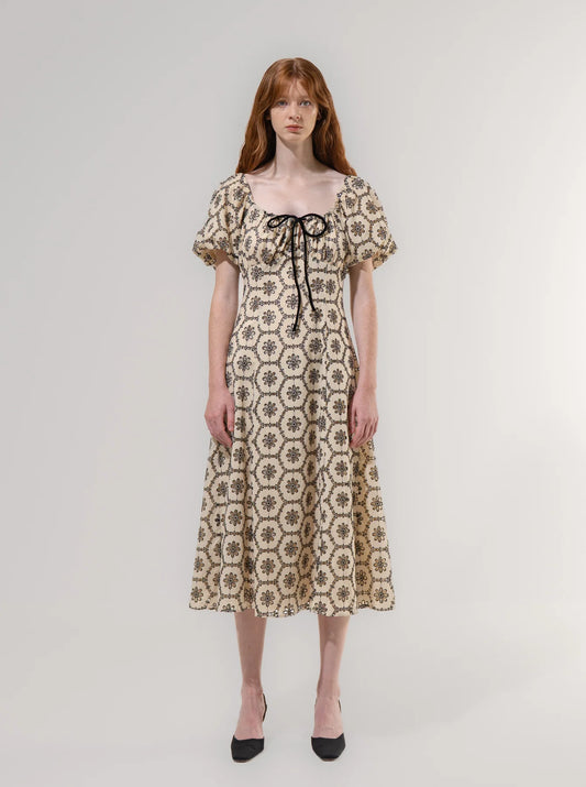 Woman wearing a floral patterned dress on a plain background