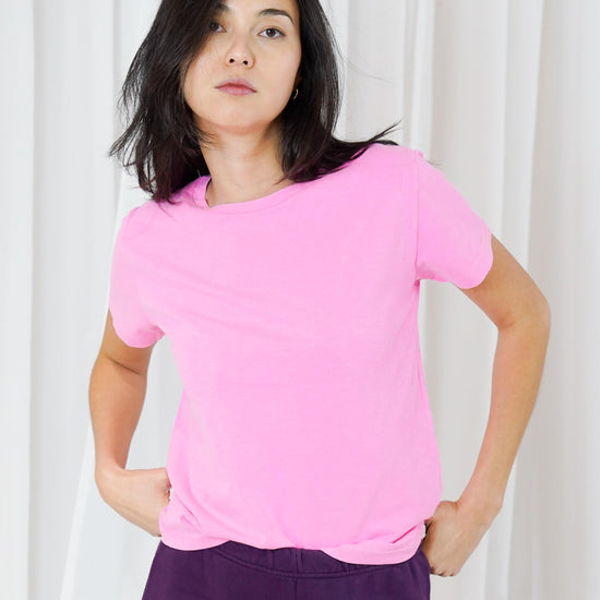 model wearing a pink t shirt and purple trousers on a plain backround