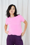 model wearing a pink t shirt and purple trousers on a plain backround