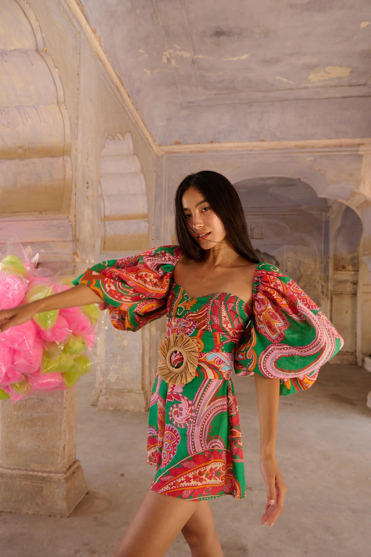 Green red and pink paisley print playsuit with oversized puff sleeves and a circle raffia belt