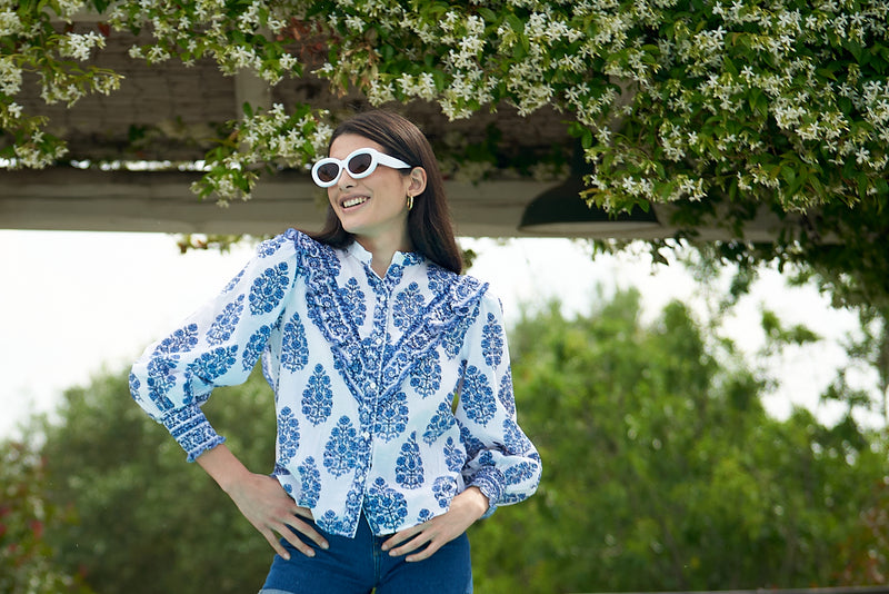 White shirt with mau collar and V shaped ruffle on the yoke with white background and blue floral print and long sleeves