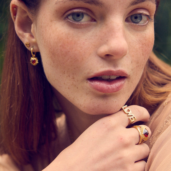gold spiky heart shaped charm earrings with red stone and huggie hoops from rachel jackson model shot