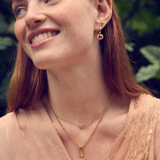 gold spiky heart shaped charm earrings with red stone and huggie hoops from rachel jackson model shot