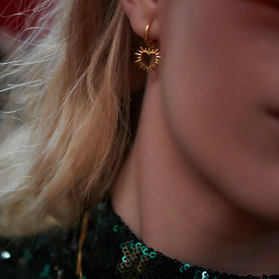 small huggie gold earrings with spiky gold heart charms from rachel jackson  model shot
