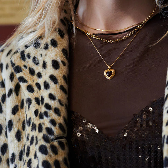 gold heart with red stone inside on a gold chain from rachel jackson model shot