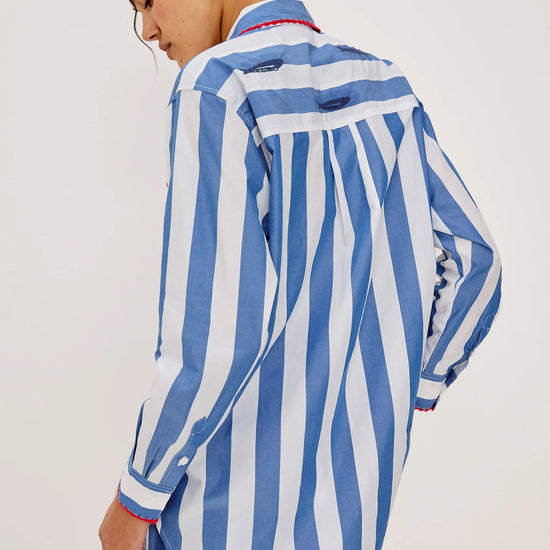 Rear view of Woman wearing a blue and white striped shirt and shorts on a plain background