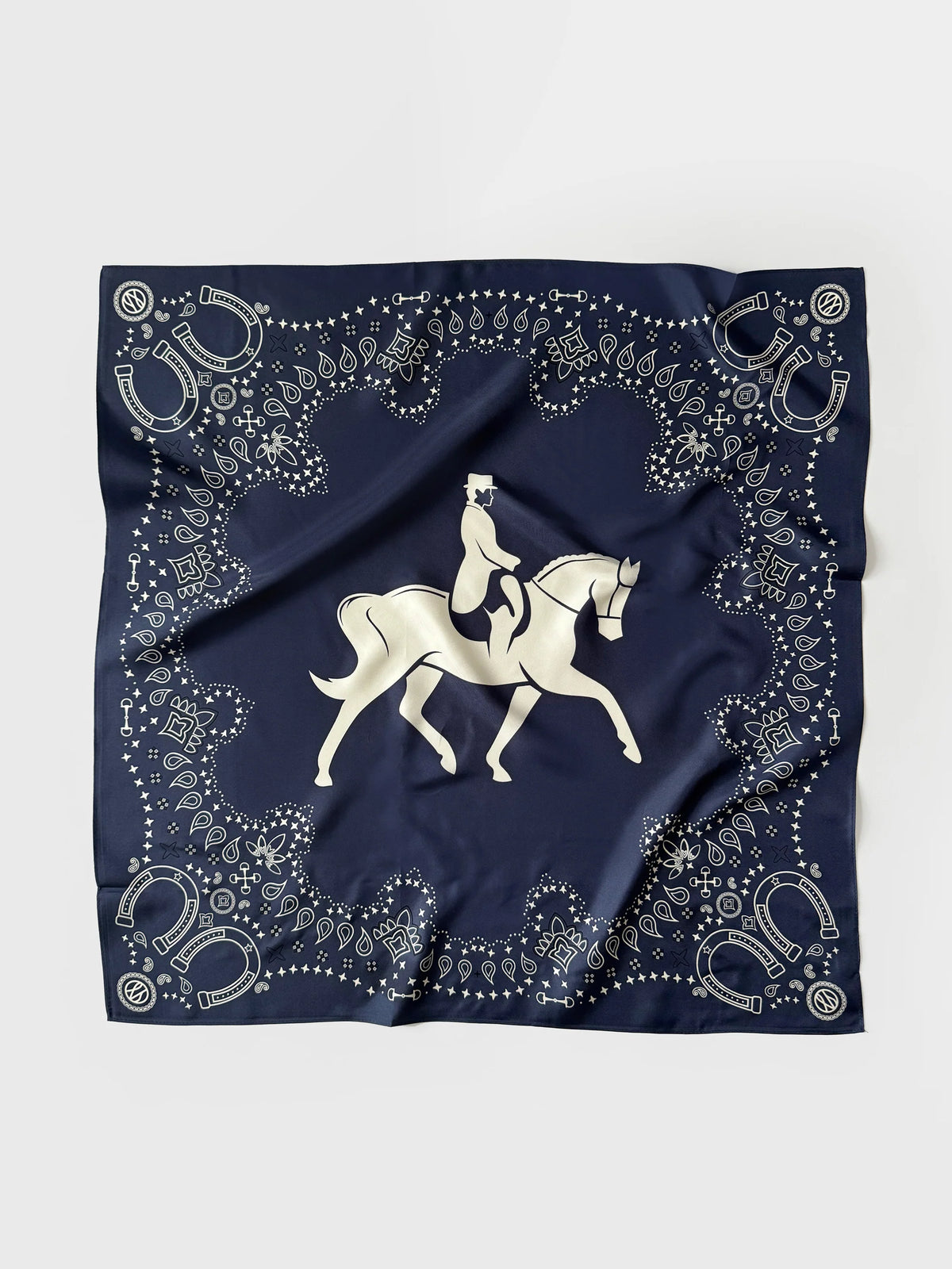 A square navy blue scarf featuring a white equestrian design in the center and an ornate border of horseshoes, dots, and decorative motifs, laid flat on a light gray background.