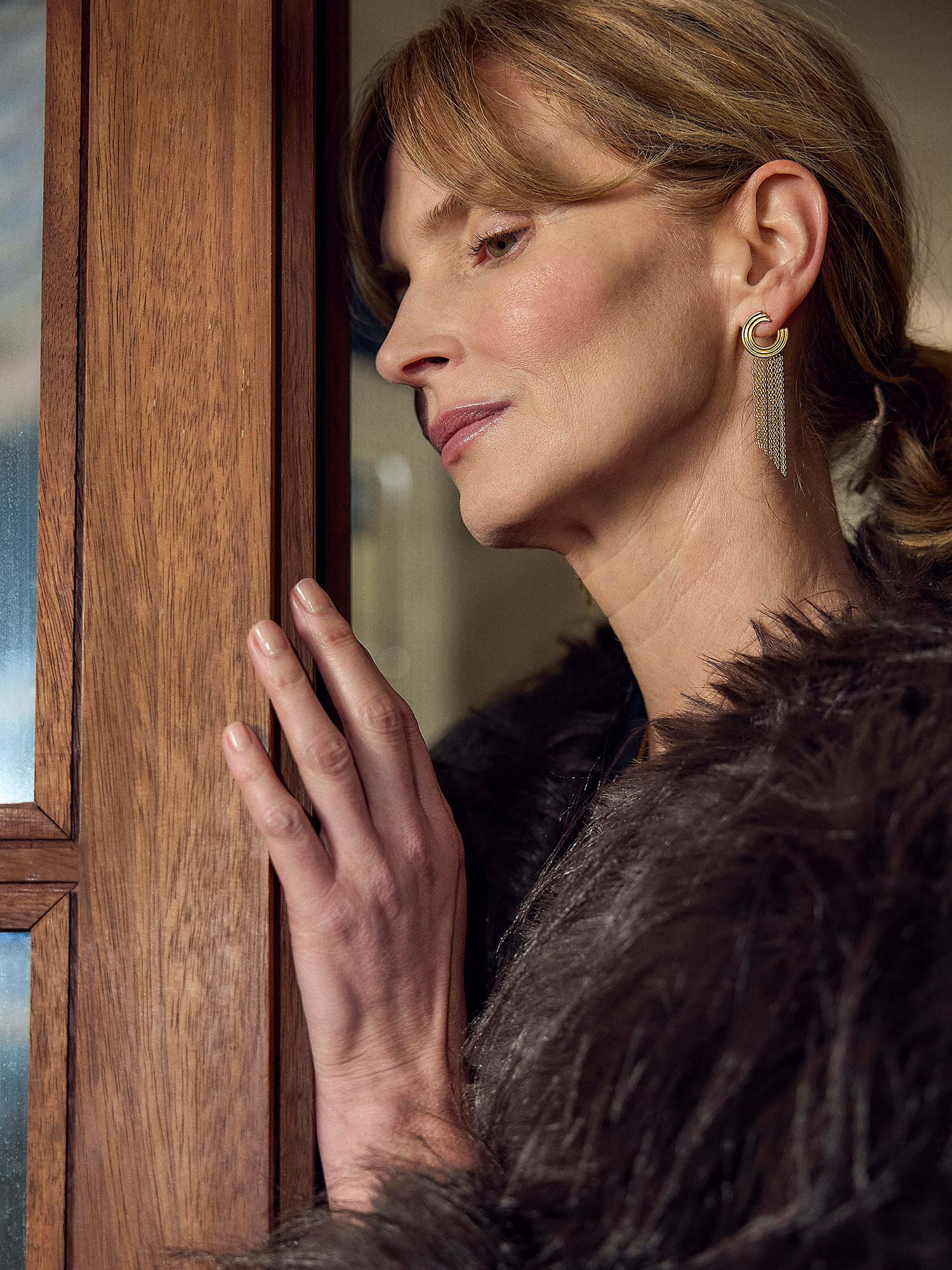 gold swirly circular hoops with chandelier style chains falling from the hoops from rachel jackson model shot