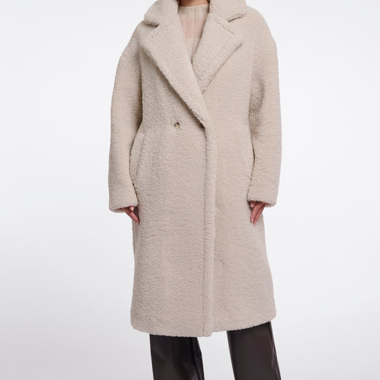 Woman wearing a long beige coat on a white background