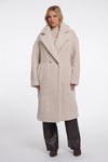 Woman wearing a long beige coat on a white background