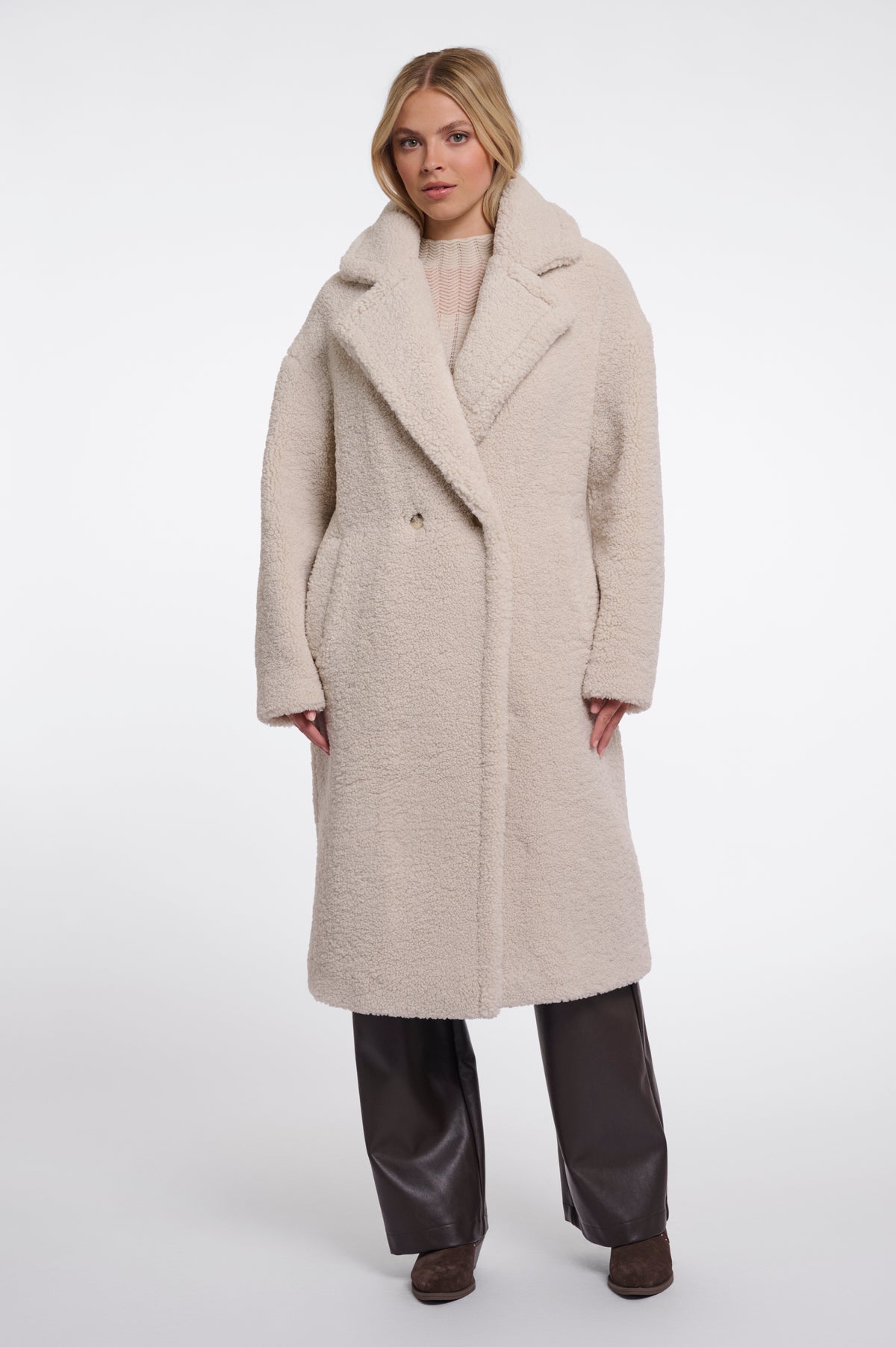 Woman wearing a long beige coat on a white background