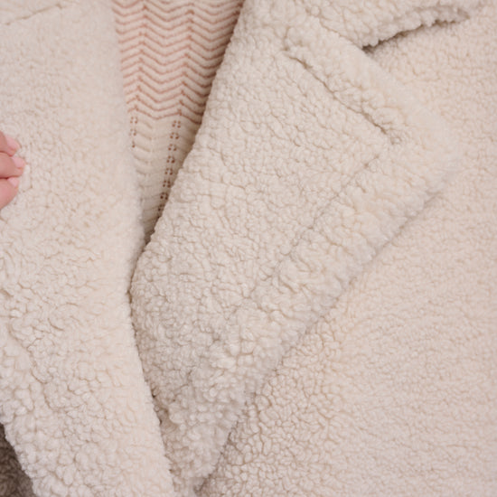 Close-up of a textured beige coat with a blurred background