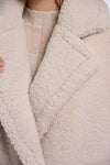Close-up of a textured beige coat with a blurred background