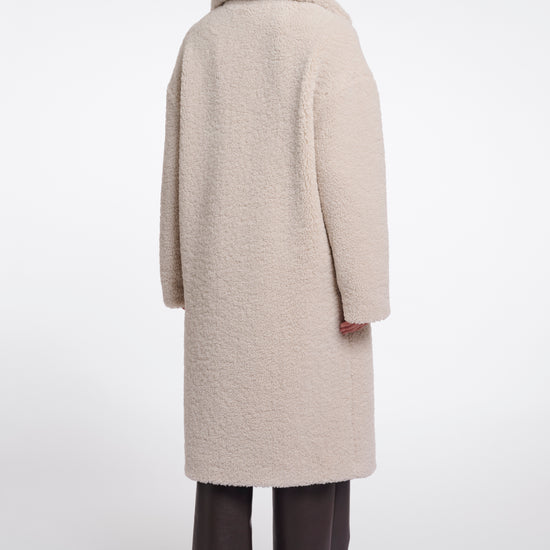 Person wearing a beige coat on a white background