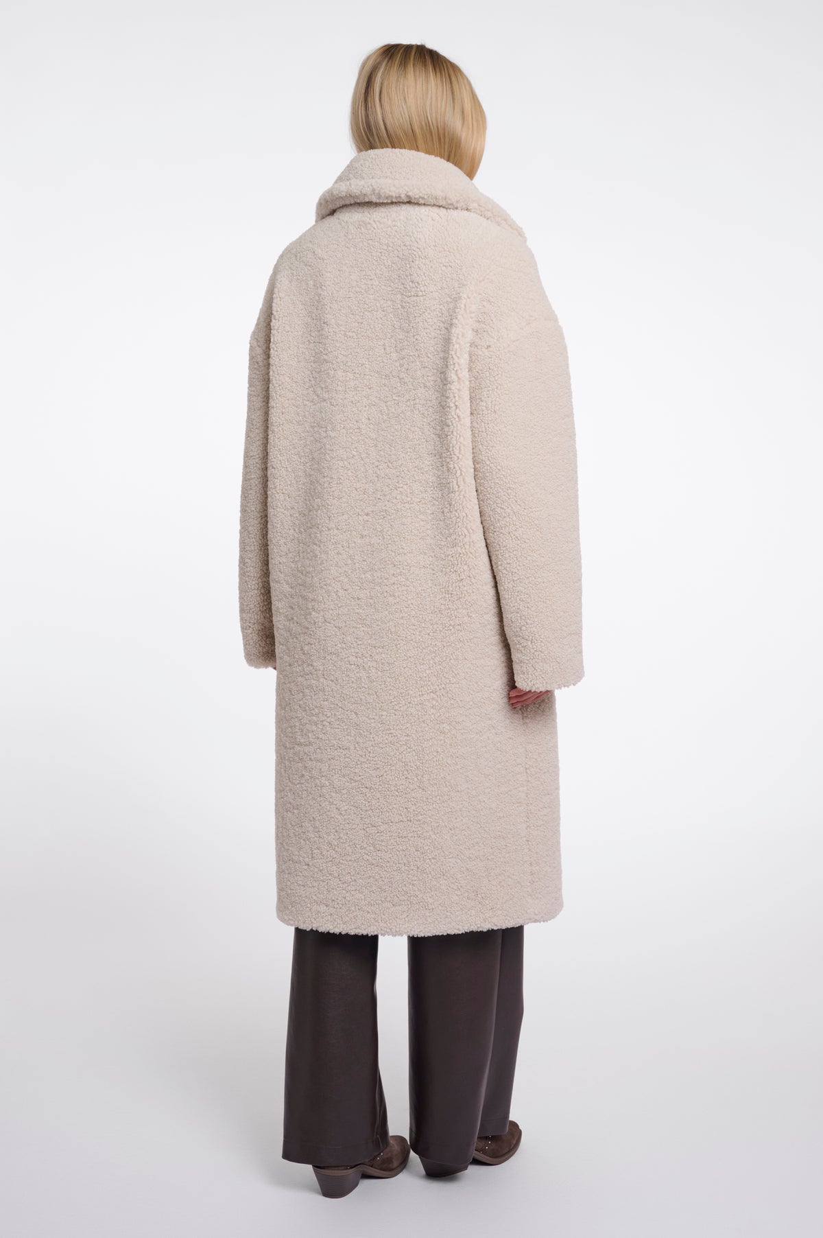 Person wearing a beige coat on a white background