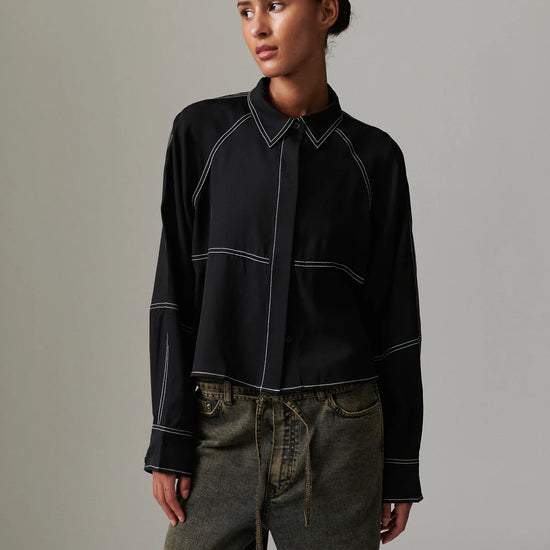 Woman wearing a black shirt with white accents against a gray background