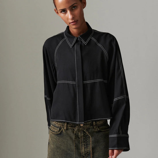 Person wearing a black shirt with white accents against a gray background