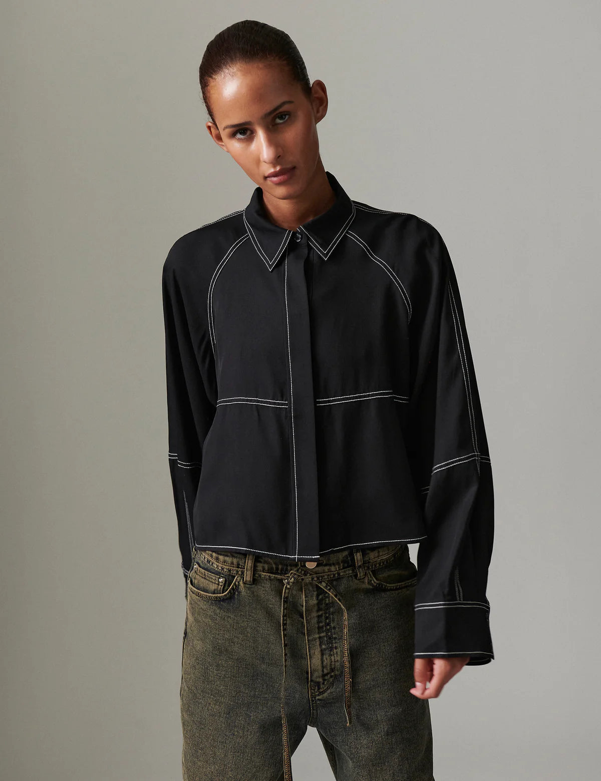 Person wearing a black shirt with white accents against a gray background