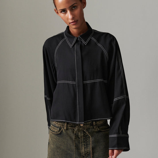 Person wearing a black shirt with white accents against a gray background