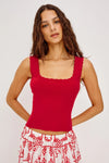 Woman wearing a red tank top and white skirt with red patterns on a plain background from Rails