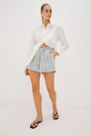 Woman wearing a white shirt and striped shorts on a white background