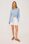 Woman wearing a blue and white Rails shirt striped shirt unbuttoned against a plain background