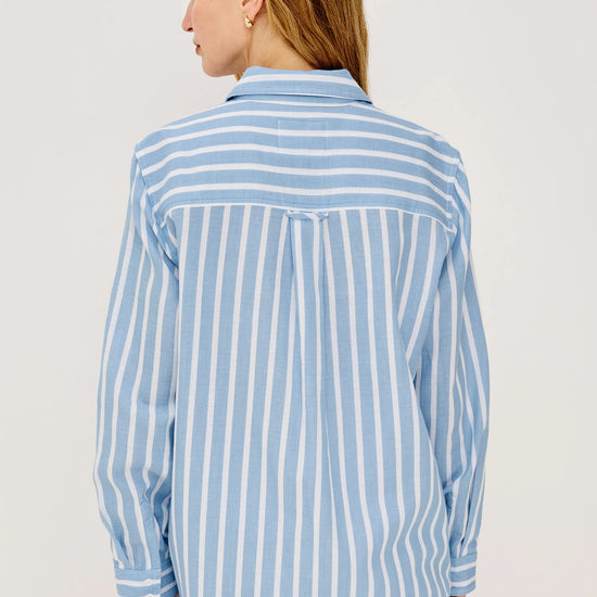 Woman wearing a blue and white Rails shirt striped shirt against a plain background rear view